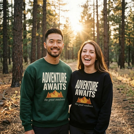 Two friends on a pine-forest trail at golden dusk wearing Adventure Awaits retro outdoors crewneck sweatshirts in Forest Green and Black