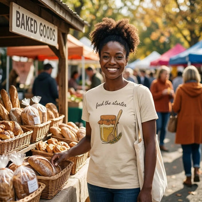 Feed The Starter sourdough baker tee in Soft Cream on a smiling woman at a farmers market bread stall