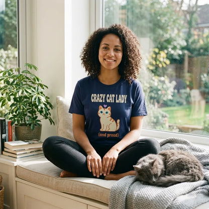 Woman relaxing on a window seat with a grey cat, wearing the Crazy Cat Lady and Proud retro Y2K tee in Navy