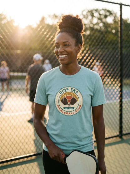 Dink Era Pickleball Club tee on a player in Heather Prism Dusty Blue — courtside golden-hour