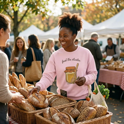 Feed The Starter sourdough crewneck — woman at a farmers market bread stall, Light Pink sweatshirt