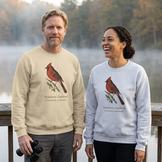 Two friends birdwatching at a misty lakeside at dawn, wearing the Northern Cardinal vintage field-guide crewneck sweatshirt in Sand and Ash