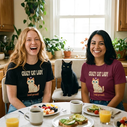 Two women friends laughing at a sunny brunch with a black cat, wearing the Crazy Cat Lady and Proud retro Y2K tee in Black and Maroon