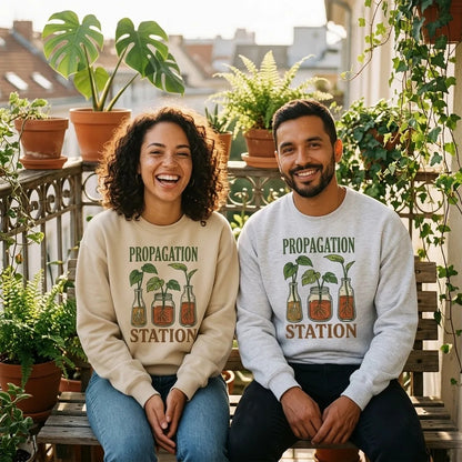 Propagation Station plant lover crewneck — two friends wearing Sand and Ash on a plant-filled balcony