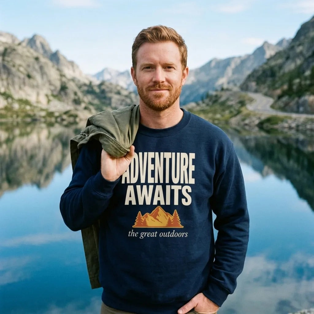 Man at an alpine lake overlook wearing a Navy Adventure Awaits retro outdoors crewneck sweatshirt