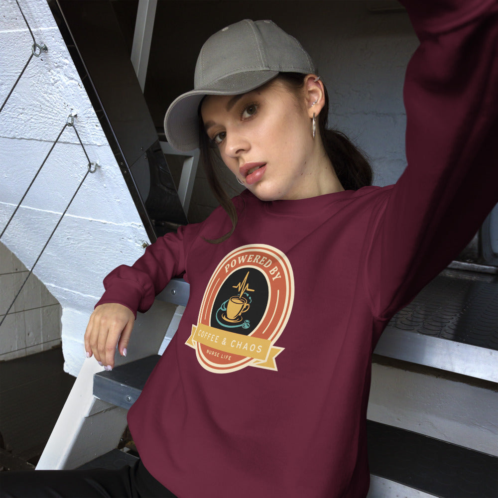Powered by Coffee & Chaos retro nurse badge crewneck sweatshirt — Maroon, on model