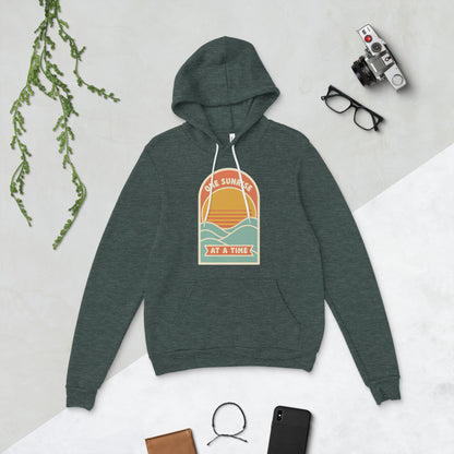 One Sunrise at a Time retro sunrise hoodie — Heather Forest, flat lay